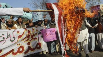 Varias personas queman una bandera estadounidense durante una manifestación contra la quema de ejemplares del Corán.