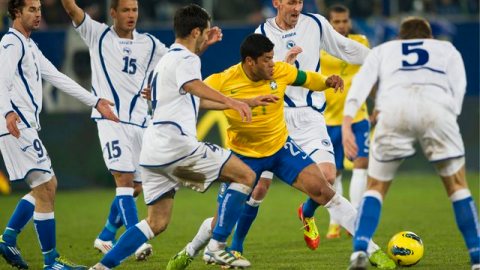 El brasileño Hulk se mueve entre cinco defensas de Bosnia para lanzar un centro al área de Bosnia.