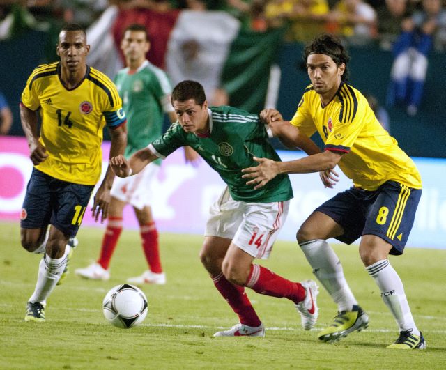Los jugadores de Colombia, Luis Perea (i) y Abel Aguilar, disputan el balón con Javier Hernández.
