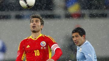 El uruguayo Walter Gargano (der.) marca al rumano  Adrian Mutu, quien controla el balón en el encuentro amistoso de ayer.