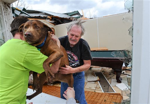Un vecino presta ayuda a Greg Cook, quien acaba de salvar a su perrito de los escombros en que hoy quedó convertida su residencia en Alabama.