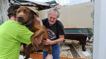 Un vecino presta ayuda a Greg Cook, quien acaba de salvar a su perrito de los escombros en que hoy quedó convertida su residencia en Alabama.