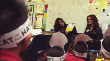 Dianna Spinale y Kelsey Saunders porristas de Los Angeles Lakers leen libros de Dr. Seuss a los pequeños estudiantes.