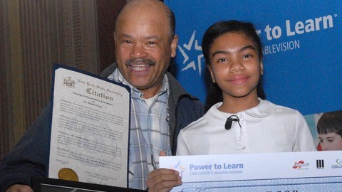 El orgulloso padre Rufino Araujo acompaña a su hija Alondra quien muestra su premio luego de participar con éxito en un concurso de ensayo literario.