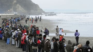 Un grupo de personas  une  sus manos en una oración en la playa ayer en conmemoración de las víctimas del terremoto y tsunami del 11 de marzo de 2011.