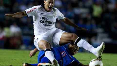 El jugador de Cruz Azul Gerardo Flores (i) despeja el balón ante la marca de Jorge Henrique de Souza (d), de Corinthians.