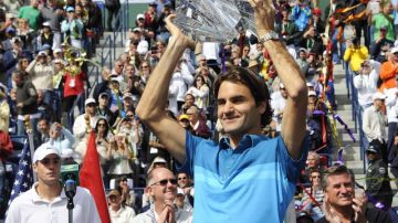 Roger Federer alza feliz  su trofeo agradeciendo la ovación de la concurrencia  que le aplaude de pie.