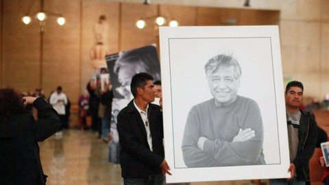 Dos trabajadores cargan la foto de Chávez.