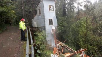 Los bomberos Greg Martin y Tim Williams estudian cómo ayudar en esta situación: Los fuertes vientos y la lluvia provocaron que esta casa se partiera en dos en Camp Meeker, en el condado de Sonoma, en California.