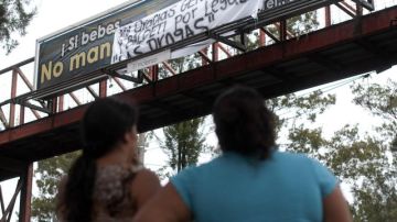 Residentes del Departamento de El Petén, leen el mensaje de advertencia colocado por el cartel frente a una escuela.
