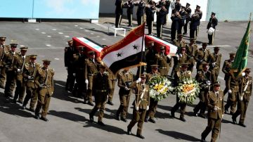 Policías sirios cargan los féretros de varios de sus compañeros durante funeral en Damasco.