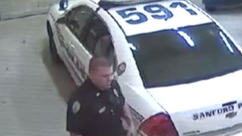 Zimmerman mira hacia abajo mientras habla con un policía.