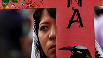 Una manifestante sostiene una cruz con el nombre de una mujer asesinada en Juárez.