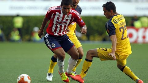 Paul Aguilar (d) de América disputa el balón con Miguel Ponce (i) de Chivas.
