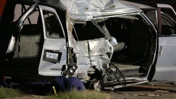 El cuerpo cubierto de una víctima yace a un lado de una camioneta luego de un accidente mortal de una camioneta que transportaba inmigrantes.