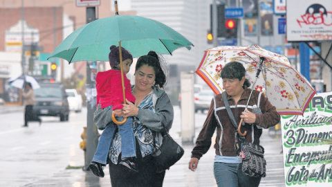 Residentes de Los Ángeles se cubren del mal tiempo que azotó la región y que dejó fuertes lluvias.