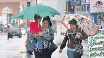 Residentes de Los Ángeles se cubren del mal tiempo que azotó la región y que dejó fuertes lluvias.