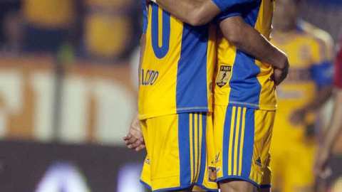 Carlos Salcido (izq.) y Alan Pulido se abrazan ante un jugador de Chivas, luego de su victoria.