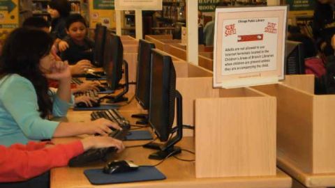 Estudiantes haciendo sus tareas con la ayuda de libros y computadoras de las Bibliotecas Públicas de Chicago.