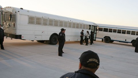 Agentes de inmigración vigilan los buses donde son llevados los indocumentados que van a ser deportados.