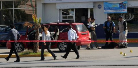 Un grupo de forenses (d) inspeccionan el cuerpo de una mujer que fue asesinada por un grupo de desconocidos cuando circulaba en su vehículo en Ciudad Juárez.