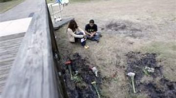 Dos amigos de las víctimas permanecen el jueves 19 de abril de 2012 junto al lugar donde fueron encontrados los cadáveres en la ciudad estadounidense de Winter Park en el estado de Florida.