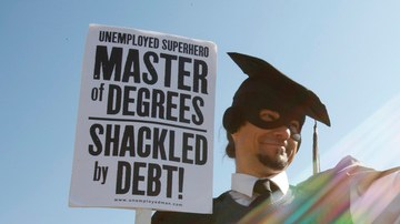 Disfrazado con una toga negra,  Gan Golan, de LA, sostiene una cadena y una pesa en representación de su deuda universitaria foto