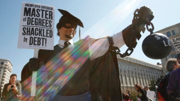 Disfrazado con una toga negra,  Gan Golan, de LA, sostiene una cadena y una pesa en representación de su deuda universitaria foto