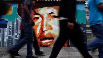 La genta camina cerca de un mural del presidente Hugo Chávez, en Caracas. El mandatario aun está en Cuba en  quimioterapia.