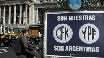 Un hombre pasa en bicicleta junto a un afiche de apoyo a la expropiación de la petrolera YPF  frente al Congreso Nacional en Buenos Aires (Argentina).