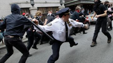 Un policía neoyorquino en momentos en que trata de golpear a uno de los manifestantes en Wall Street con su porra  policial.