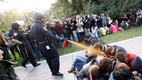 Un agente de la policía usa gas pimienta contra un grupo de estudiantes de la Universidad de California que realizan una protesta pacífica.
