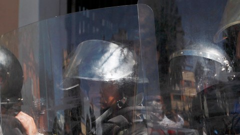 Agentes de la policia antimotines de guardia frente a  manifestantes que apoyan las protestas de los médicos en La Paz.