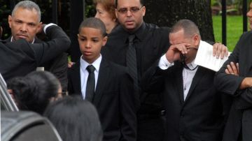 Juan González (izq.) padre de las menores fallecidos en el accidente es acompañado por su hijo mayor Jonel a la salida de la iglesia St. Raymond.