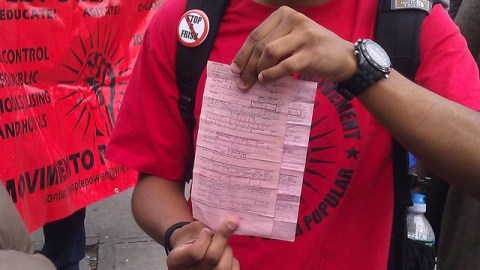 Malik Ayala, mientras participaba en la marcha de ayer, muestra la citación de la policía por conducta desordenada.