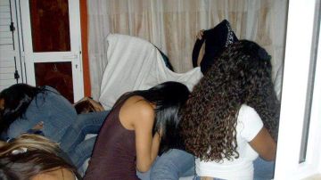 Fotografía de archivo de unas chicas tapándose durante una redada a una red dedicada a la explotación sexual de mujeres.