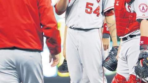 Ervin Santana (centro) devuelve la bola al mánager Mike Scioscia después de lanzar siete entradas ante los Meliizos.
