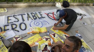 Unos jóvenes escriben lemas reivindicativos  en Madrid mientras se preparan para que los llamados 'indignados' hagan oír sus voces.