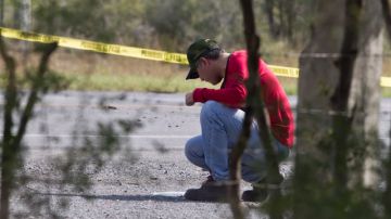 Un perito forense examina el área donde fueron hallados docenas de cuerpos desmembrados en una carretera cercana a la frontera con EEUU.