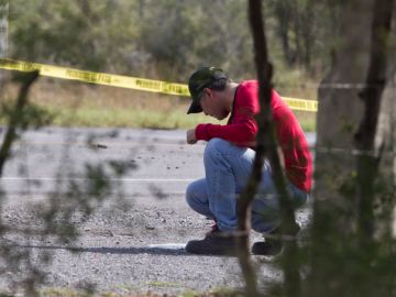 Un perito forense examina el área donde fueron hallados docenas de cuerpos desmembrados en una carretera cercana a la frontera con EEUU.