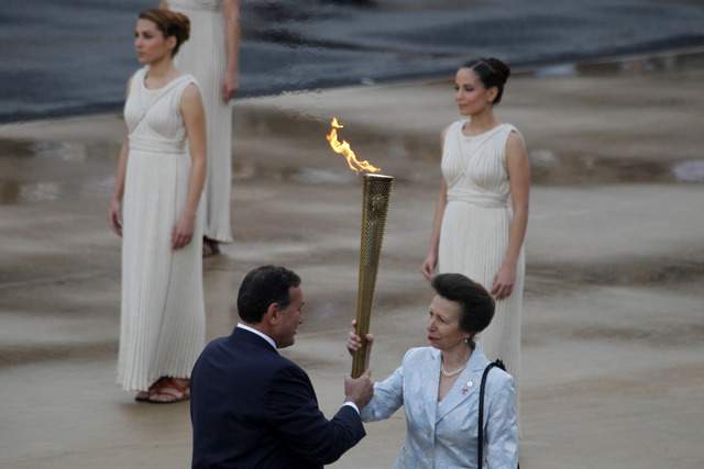 La Princesa Ana sostiene la antorcha con la flama olímpica que le entrega el presidente del Comité Olímpico Griego, Spyros Kapralos, en el Estadio Panatinaico.