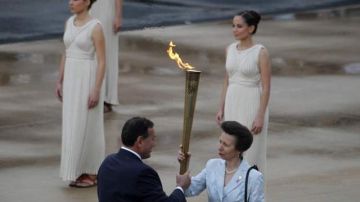La Princesa Ana sostiene la antorcha con la flama olímpica que le entrega el presidente del Comité Olímpico Griego, Spyros Kapralos, en el Estadio Panatinaico.