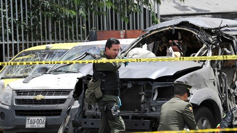 Policías colombianos inspeccionan el sitio donde explotó una bomba el martes; fue colocada en el exterior de un auto.