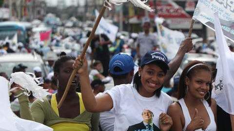 (Arriba) seguidores del candidato presidencial Danilo Medina del PLD durante el cierre de campaña al igual que manifestantes  del opositor Partido PRD, Hipólito Mejía (fuera de cuadro), quienes concluyeron el viernes los desfiles políticos.