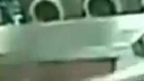 Imagen tomada del video de una cámara de seguridad en la que se ve al padre metiendo a su hijo dentro de la lavadora.