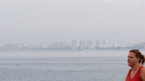 Una residente pasea por el malecón de Puerto Vallarta, México mientras que abajo se observa la trayectoria  del huracán Bud, el primero de la temporada.