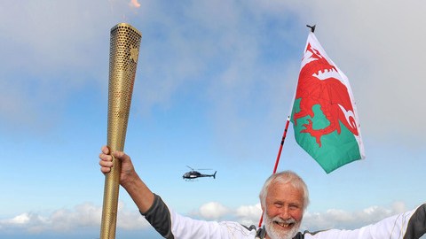 Sir Chris Bonington, miembro de la realeza inglesa, porta la antorcha antes de ser colocada en la cima del Mount Snowdon.
