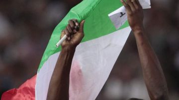 Usain Bolt pasea una bandera italiana al ganar su carrera.