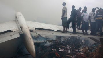 Personas paradas sobre una de las alas del avión que se estrelló sobre un barrio en Lagos.