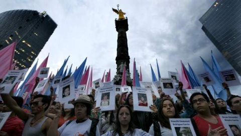 Personas sostienen imágenes de víctimas que murieron en el fuego de la Guardería ABC.
